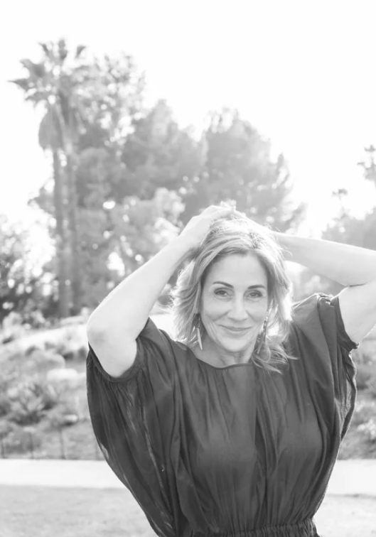 Black-and-white outdoor portrait of a woman with her arms raised