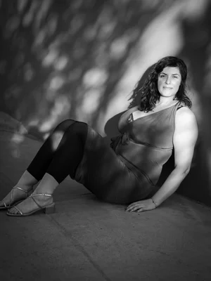 Black-and-white portrait of a woman seated on the floor against a wall